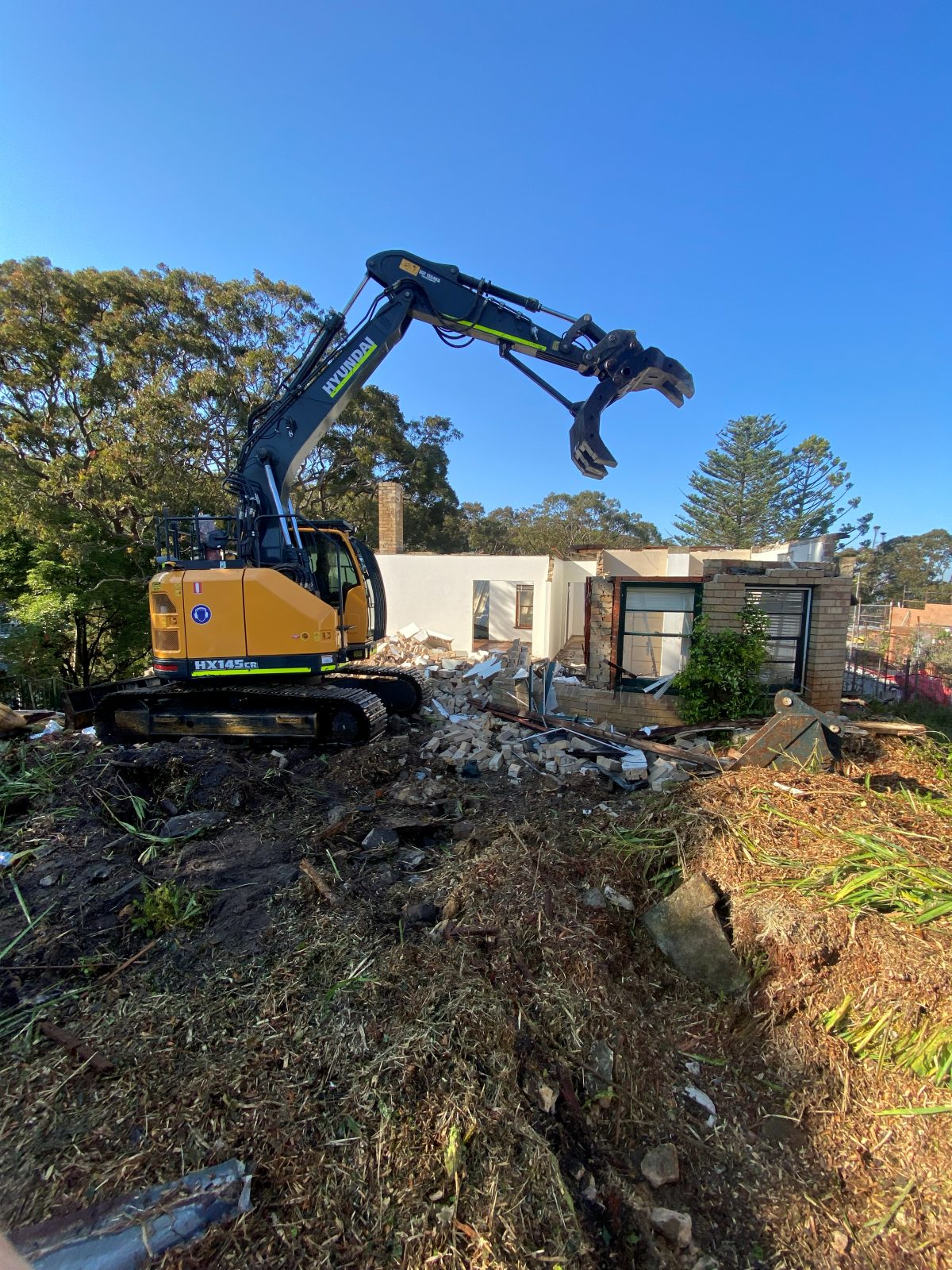 Excavator with grab demolishing a house, Mosman NSW