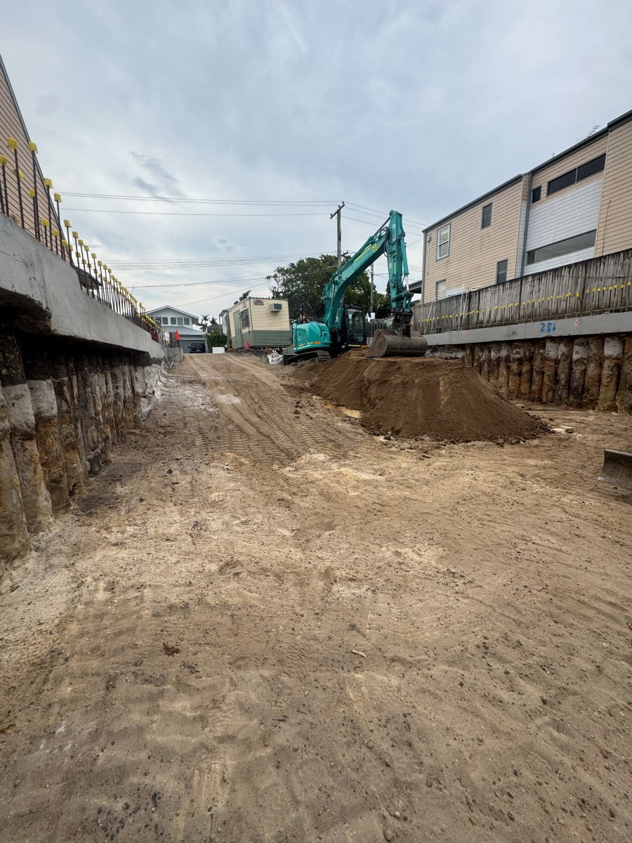 Excavator working between shored boundary walls in a basement cut, Freshwater NSW